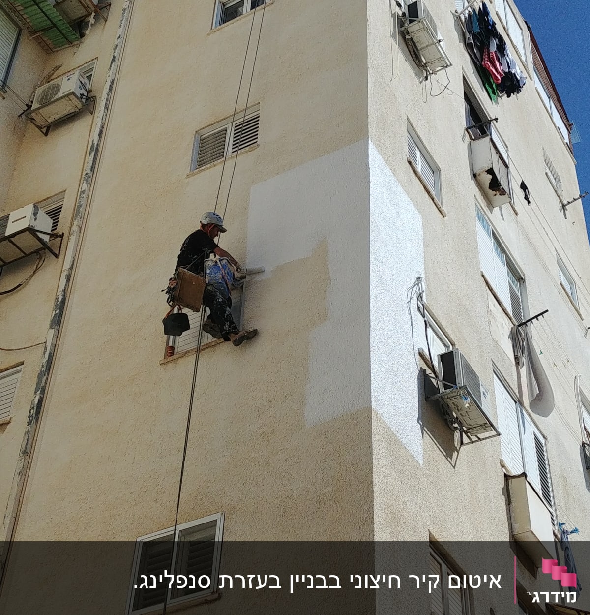 אדם צובע קיר חיצוני של בניין גבוה